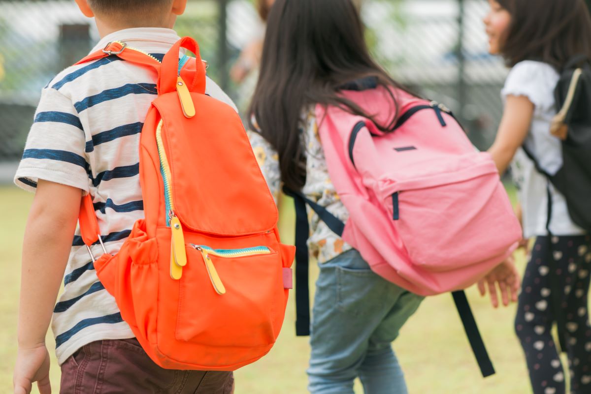 three pupils primary school go hand hand boy girl with school bags back beginning school lessons warm day fall back school little first graders