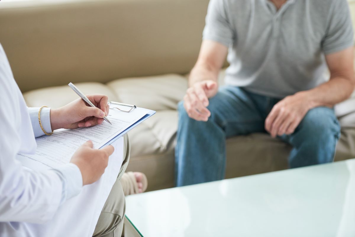 unrecognizable female doctor talking patient writing house call