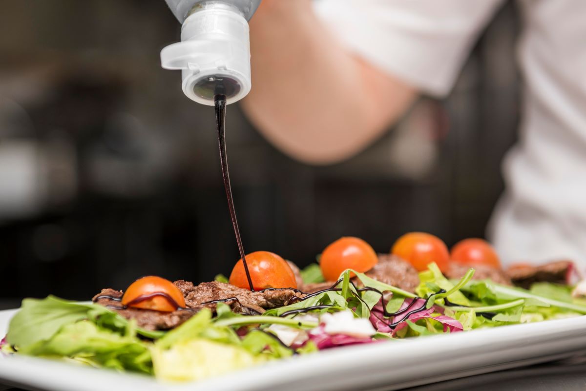 chef squeezing sauce salad